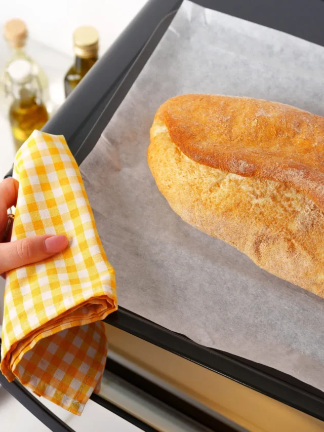Pagnotta di pane appena sfornata su una teglia con carta forno, pronta per essere rigenerata in forno dopo lo scongelamento.