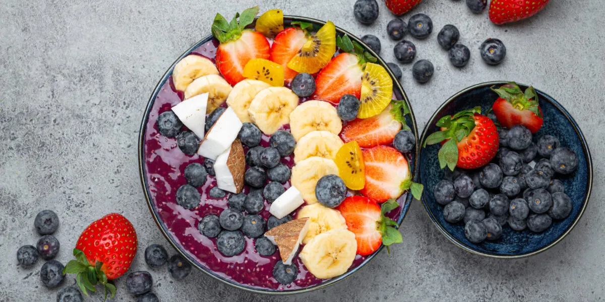 Acai bowl con frutta fresca, banana, fragole, mirtilli e cocco: colazione fit ricca di antiossidanti e fibre.