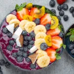 Acai bowl con frutta fresca, banana, fragole, mirtilli e cocco: colazione fit ricca di antiossidanti e fibre.