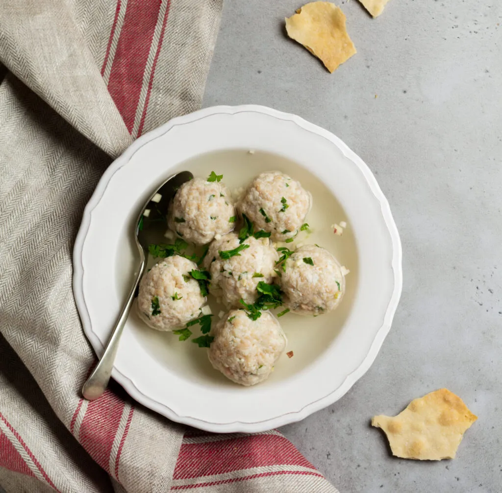 Canederli con pane raffermo serviti in brodo con prezzemolo fresco