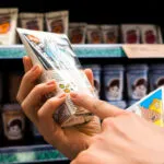 Mani che leggono l’etichetta nutrizionale di un prodotto alimentare al supermercato.