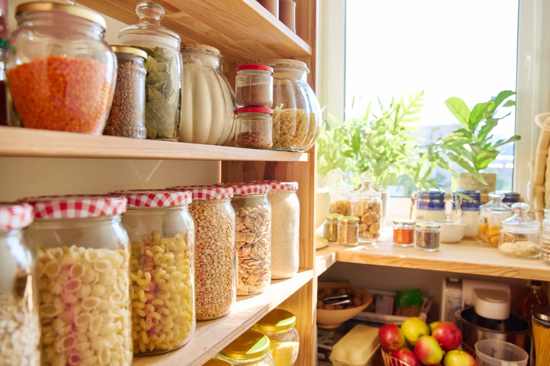Dispensa fit organizzata con barattoli di vetro pieni di cereali, pasta, legumi e ingredienti sani per ricette equilibrate