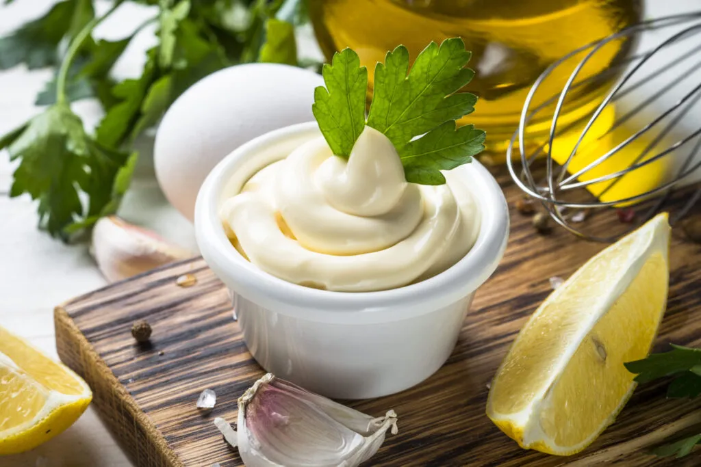 Maionese fit fatta in casa in ciotola bianca con limone, aglio, prezzemolo, uovo e olio extravergine.