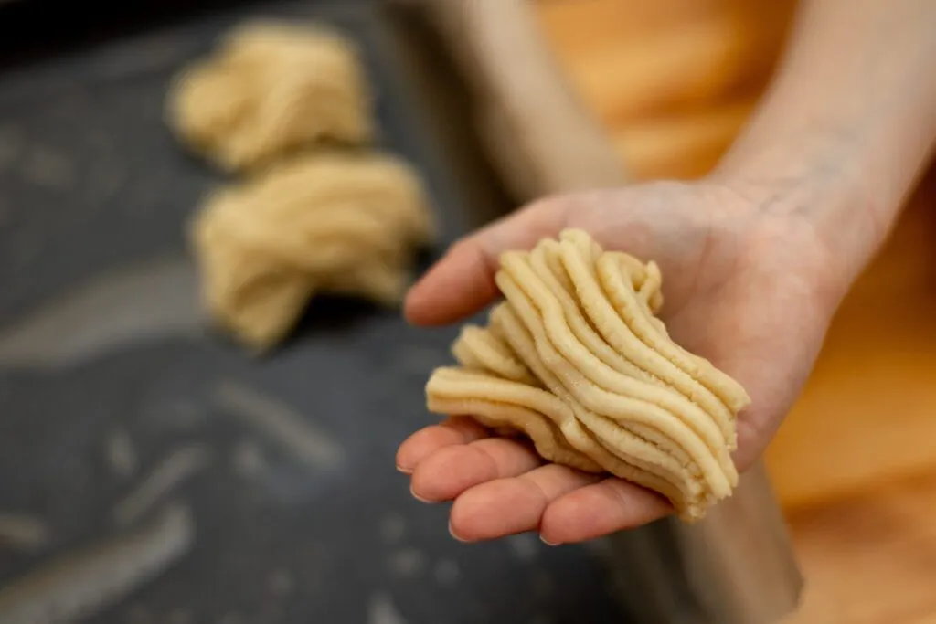 Mano che contiene una porzione di pasta fresca, usata per stimare la quantità senza ricorrere alla bilancia.