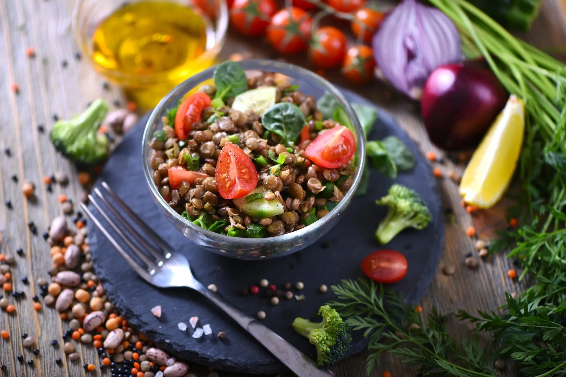 Insalata fit di lenticchie con pomodorini, cetriolo e spinaci, servita in una ciotola di vetro con verdure fresche.