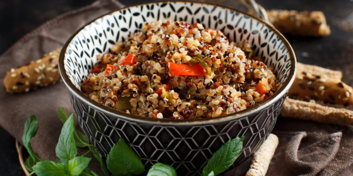 Bowl di quinoa con verdure colorate, menta fresca e grissini, ideale per ricette con quinoa fit.