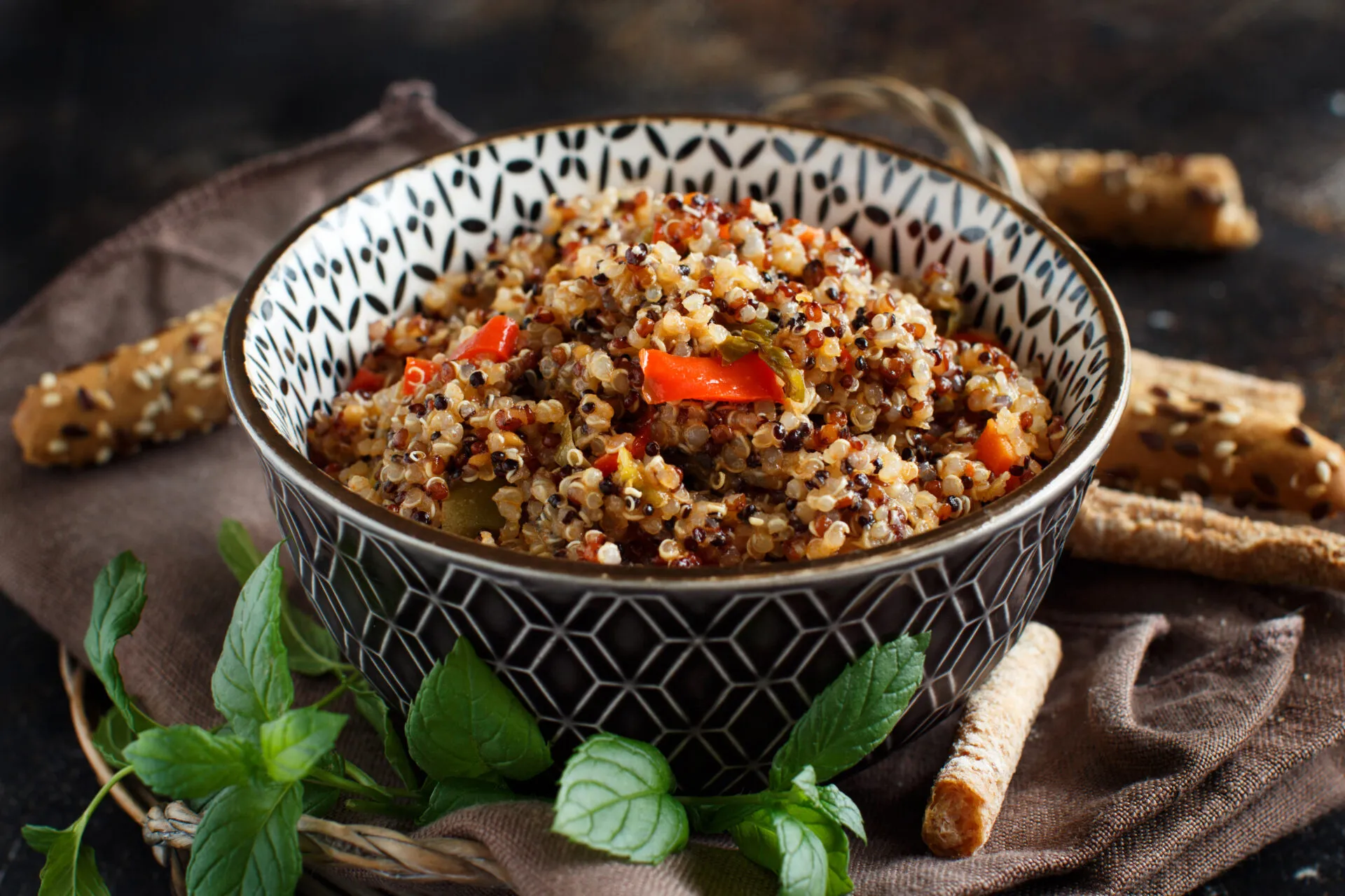 Bowl di quinoa con verdure colorate, menta fresca e grissini, ideale per ricette con quinoa fit.