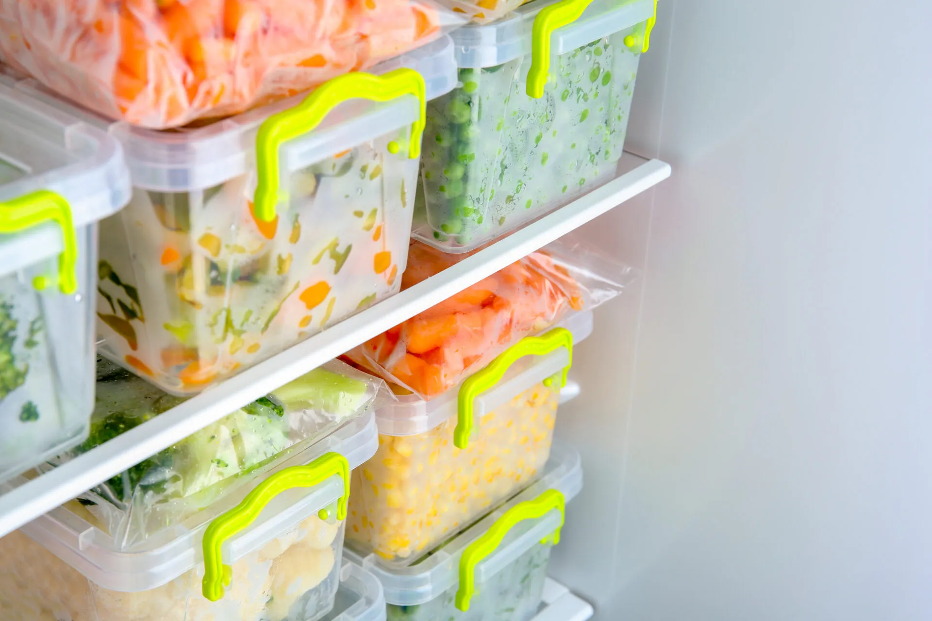 Contenitori e sacchetti con verdure e pasti pronti organizzati nel freezer