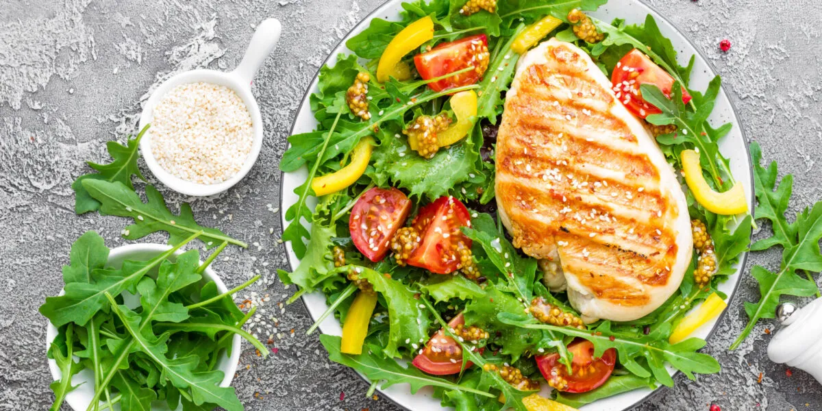 Petto di pollo grigliato su insalata di rucola, pomodorini e peperoni gialli con semi di sesamo.