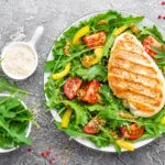 Petto di pollo grigliato su insalata di rucola, pomodorini e peperoni gialli con semi di sesamo.