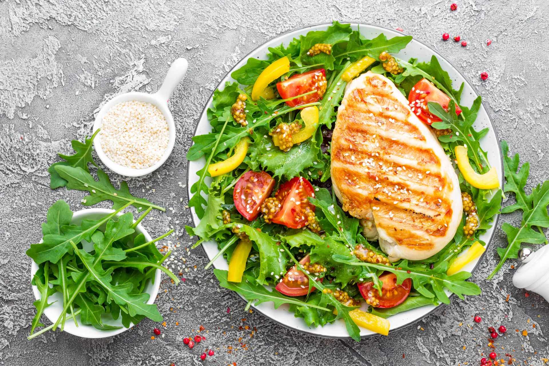 Petto di pollo grigliato su insalata di rucola, pomodorini e peperoni gialli con semi di sesamo.
