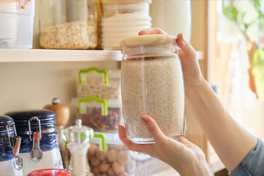 Barattolo di riso in una dispensa fit organizzata con cereali e ingredienti sani conservati in cucina