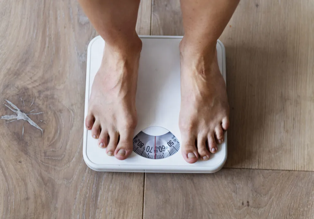 Persona in piedi su una bilancia durante una dieta, simbolo dello stallo del peso e del monitoraggio dei progressi.