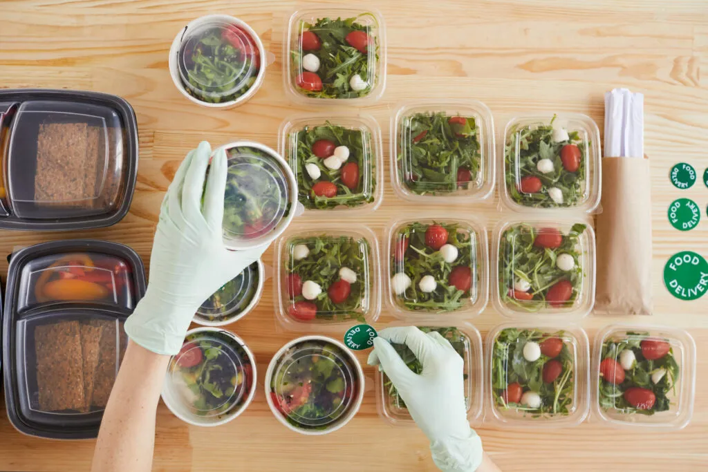 Contenitori con insalate pronte per batch cooking fit su tavolo in legno.