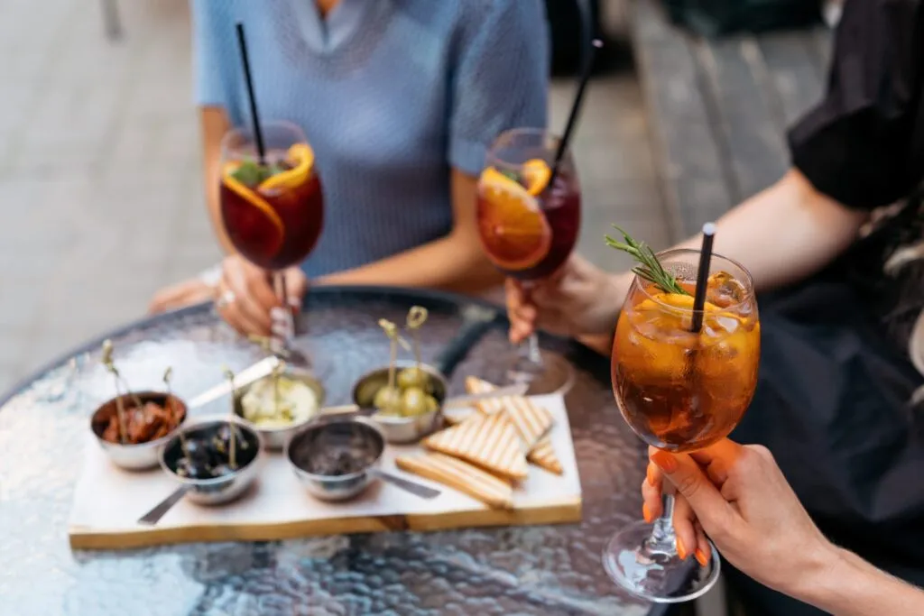 Persone che condividono un aperitivo con cocktail e stuzzichini, simbolo della vita sociale che può convivere con un'alimentazione equilibrata.