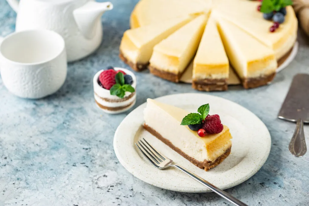 Cheesecake fit a fette con base croccante, crema leggera e decorazione di lamponi, mirtilli e menta.
