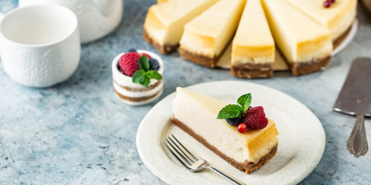 Cheesecake fit a fette con base croccante, crema leggera e decorazione di lamponi, mirtilli e menta.