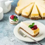 Cheesecake fit a fette con base croccante, crema leggera e decorazione di lamponi, mirtilli e menta.
