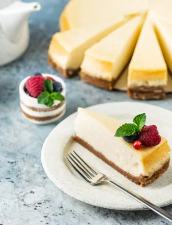 Cheesecake fit a fette con base croccante, crema leggera e decorazione di lamponi, mirtilli e menta.