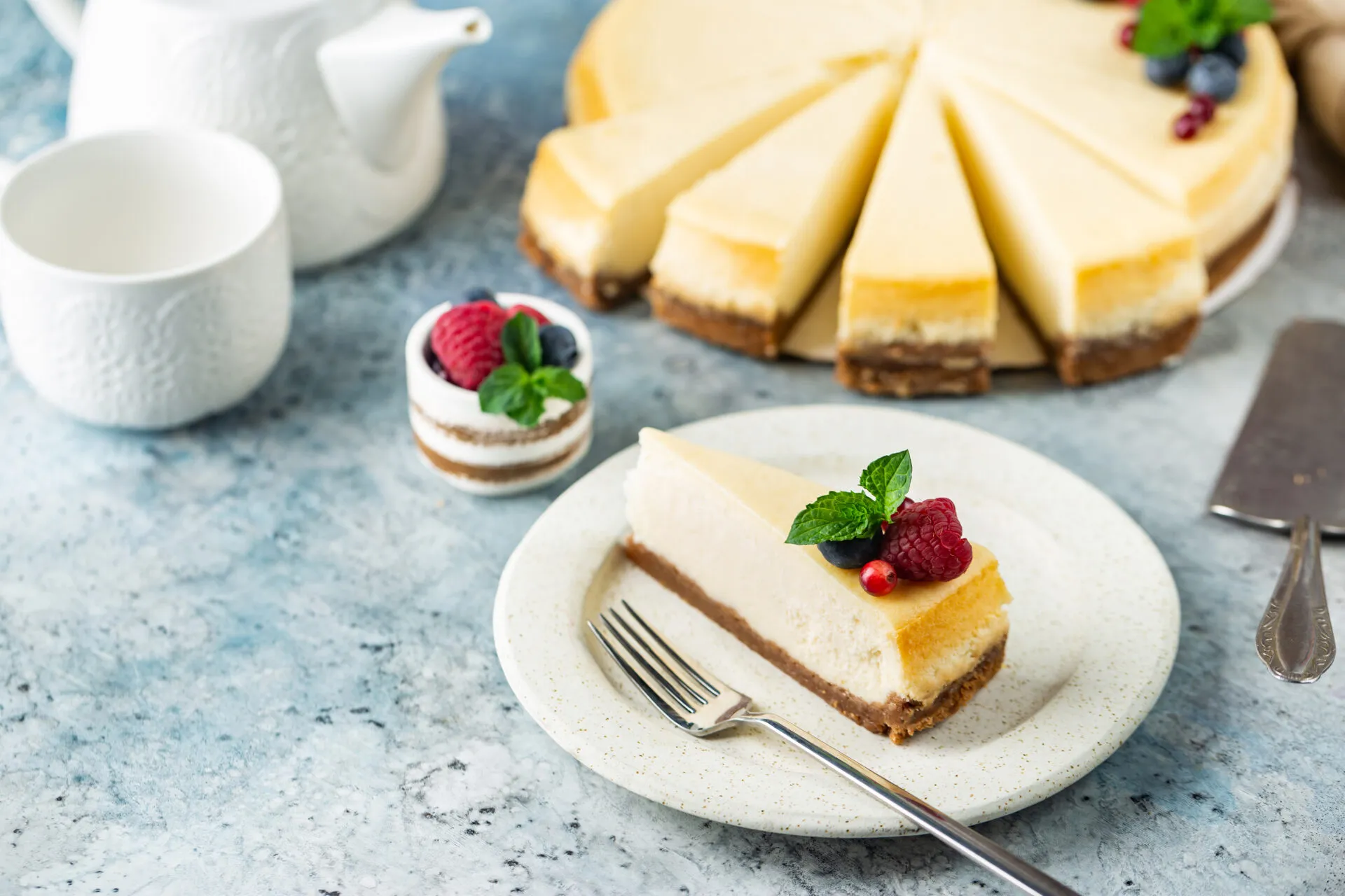 Cheesecake fit a fette con base croccante, crema leggera e decorazione di lamponi, mirtilli e menta.