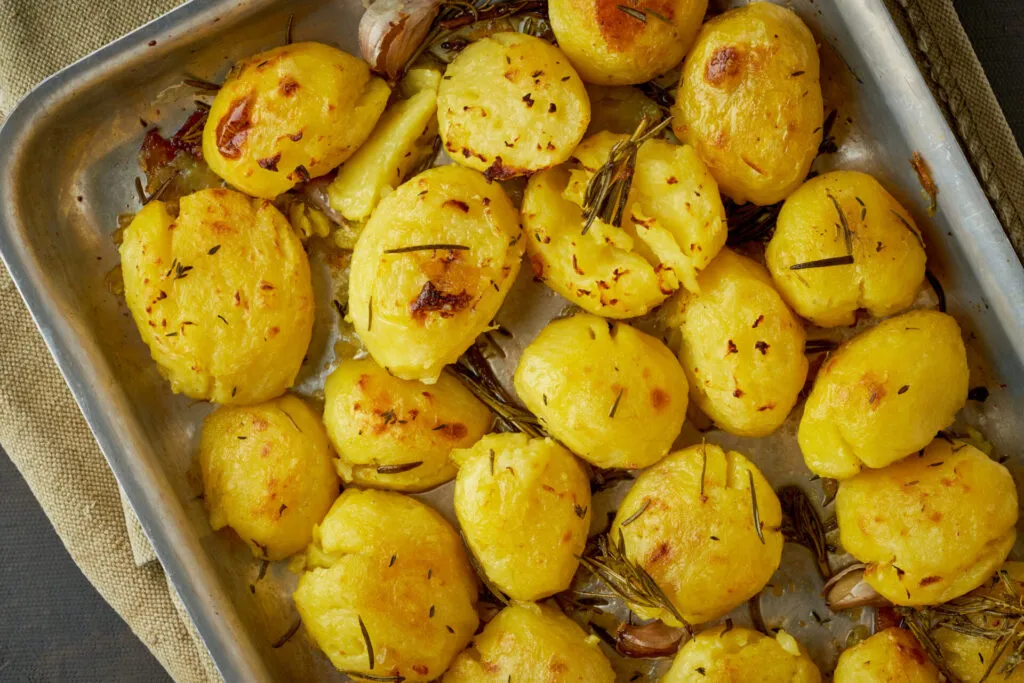 Patate al forno dorate con rosmarino in teglia di metallo