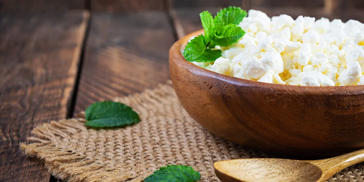 Fiocchi di latte in una ciotola di legno con foglie di menta fresca