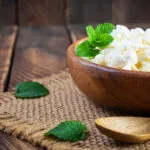Fiocchi di latte in una ciotola di legno con foglie di menta fresca