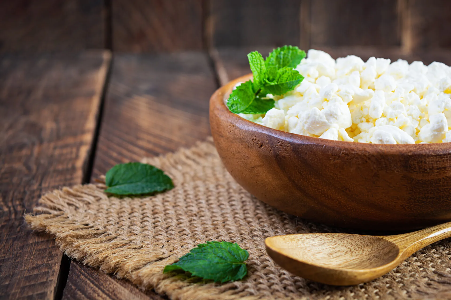 Fiocchi di latte in una ciotola di legno con foglie di menta fresca