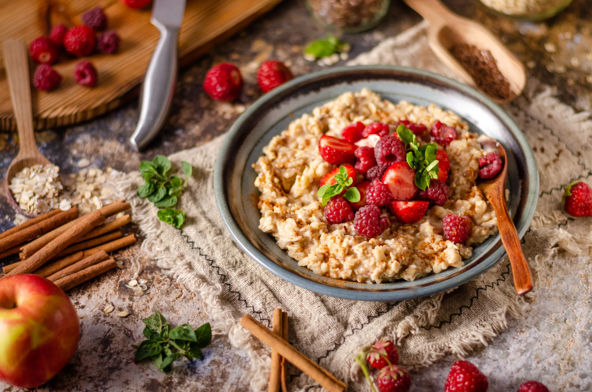 Overnight oats cremosi con fragole, lamponi, cannella e foglie di menta serviti in una ciotola.