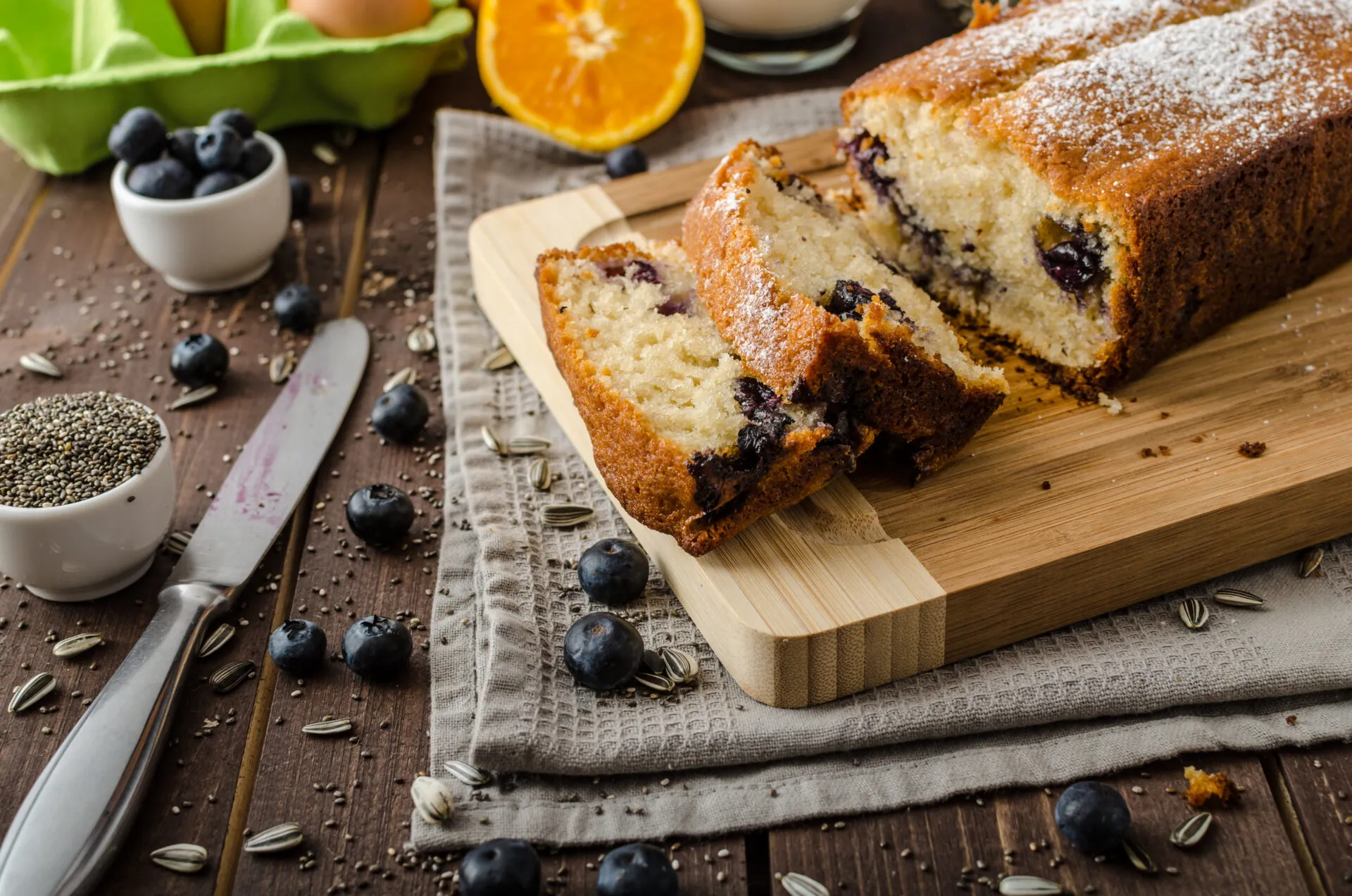Plumcake fit ai mirtilli tagliato a fette e spolverato con zucchero a velo su un tagliere di legno.