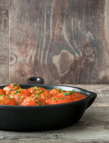 Polpette fit al sugo di pomodoro con prezzemolo in padella di ghisa nera