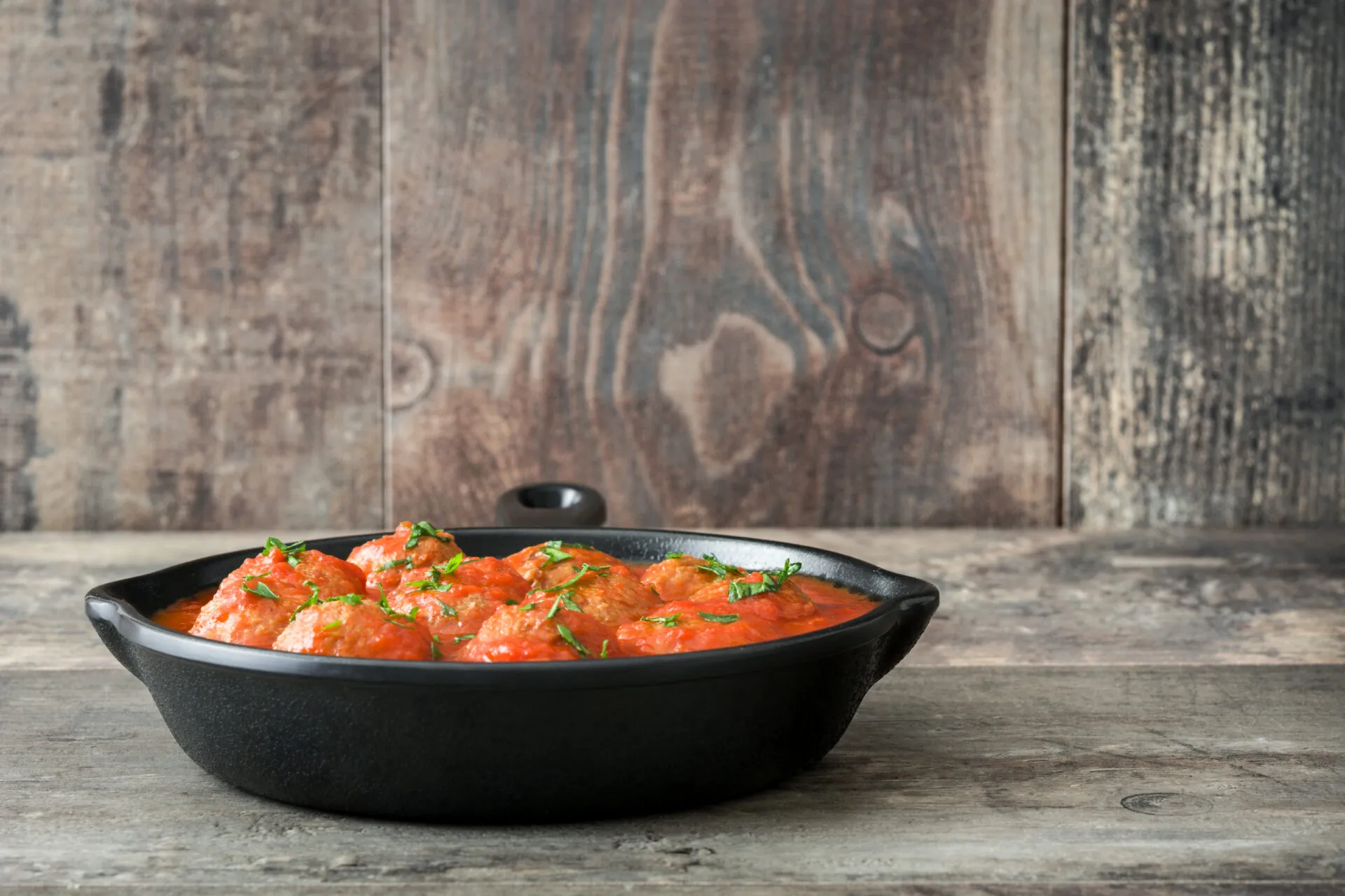 Polpette fit al sugo di pomodoro con prezzemolo in padella di ghisa nera