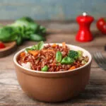 Bowl di riso integrale con broccoli, carote, piselli e foglie di basilico.