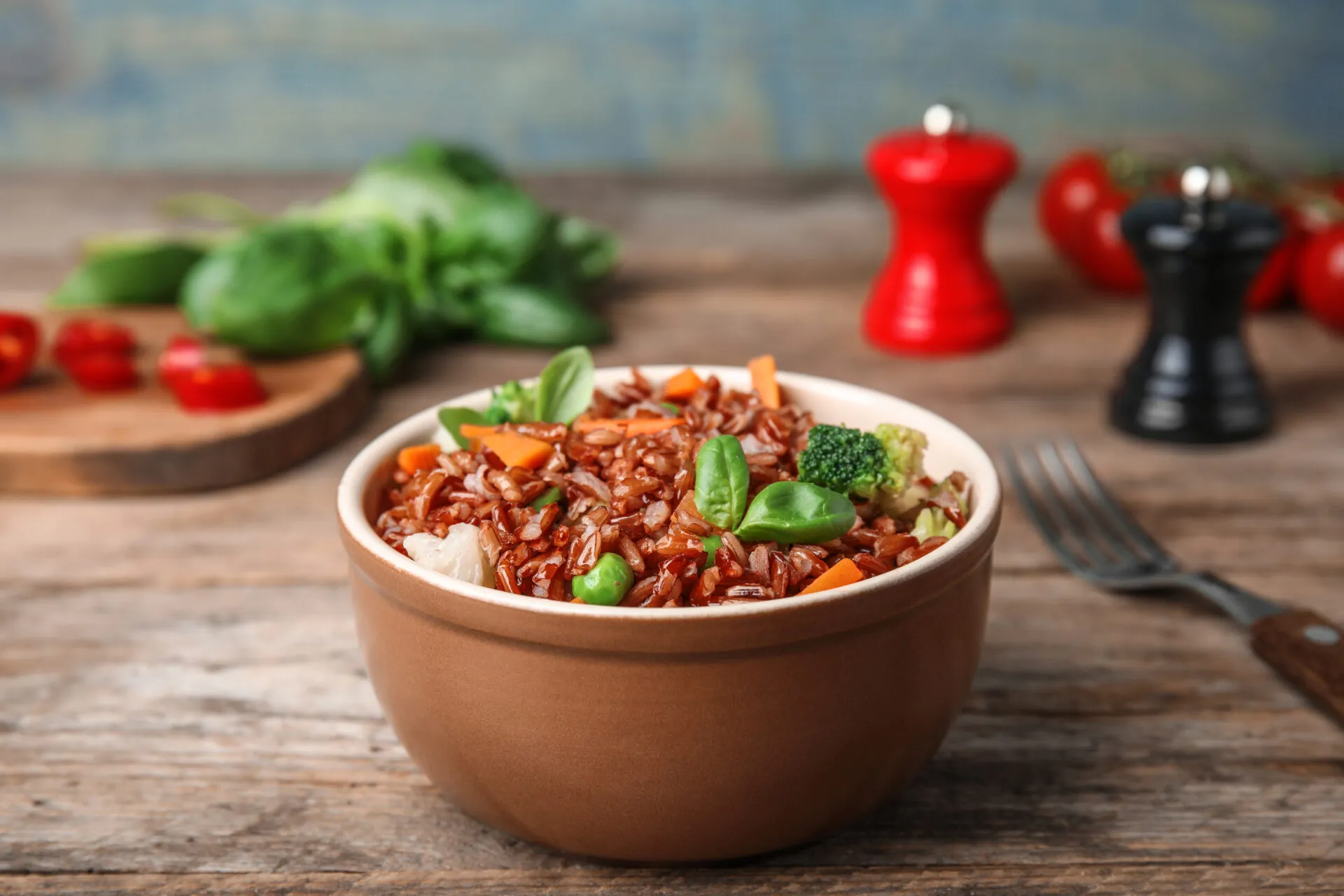 Bowl di riso integrale con broccoli, carote, piselli e foglie di basilico.