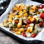 Verdure miste al forno a cubetti su teglia con carta forno