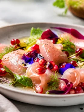 Carpaccio di ricciola con melograno, lime, zenzero e misticanza