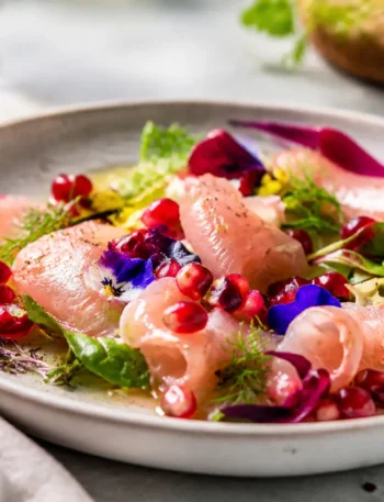 Carpaccio di ricciola con melograno, lime, zenzero e misticanza