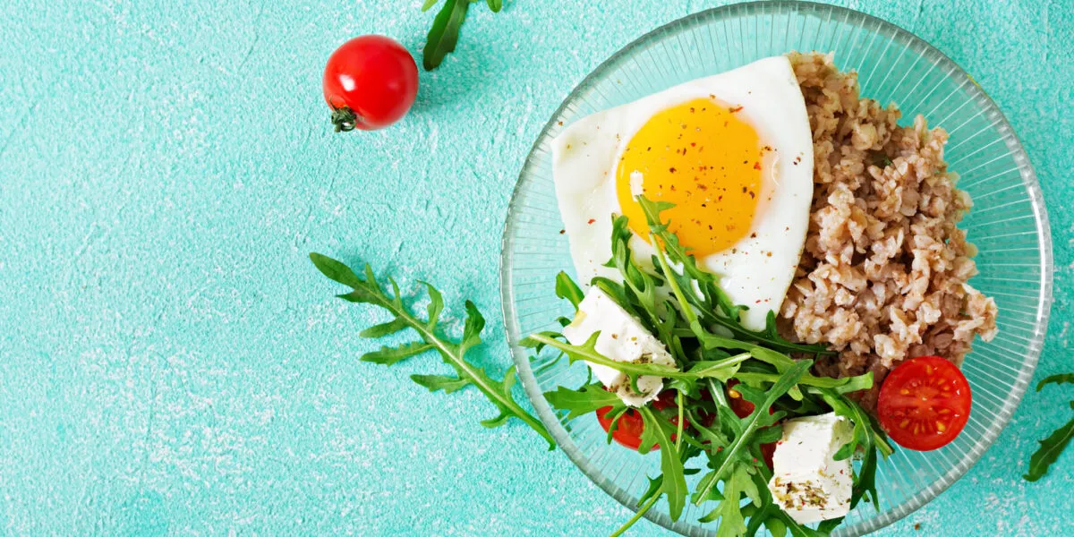 Piatto con uovo all'occhio di bue, cereali, rucola, feta e pomodorini