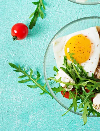 Piatto con uovo all'occhio di bue, cereali, rucola, feta e pomodorini