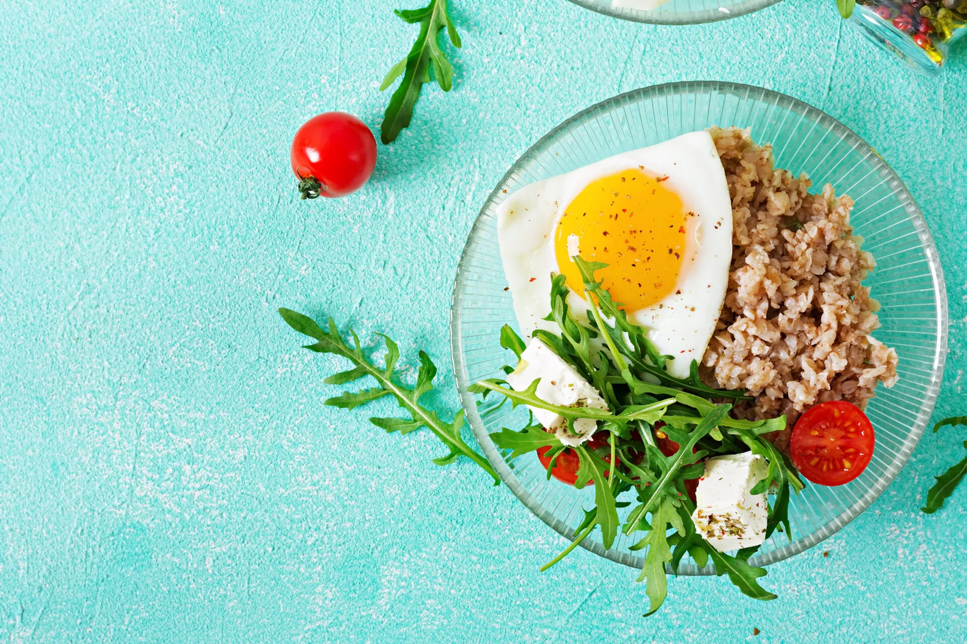 Piatto con uovo all'occhio di bue, cereali, rucola, feta e pomodorini