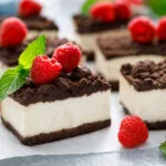 Quadrotti di cheesecake con base al cacao, crema bianca e lamponi