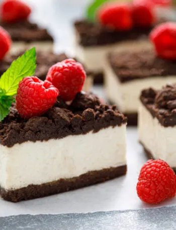 Quadrotti di cheesecake con base al cacao, crema bianca e lamponi