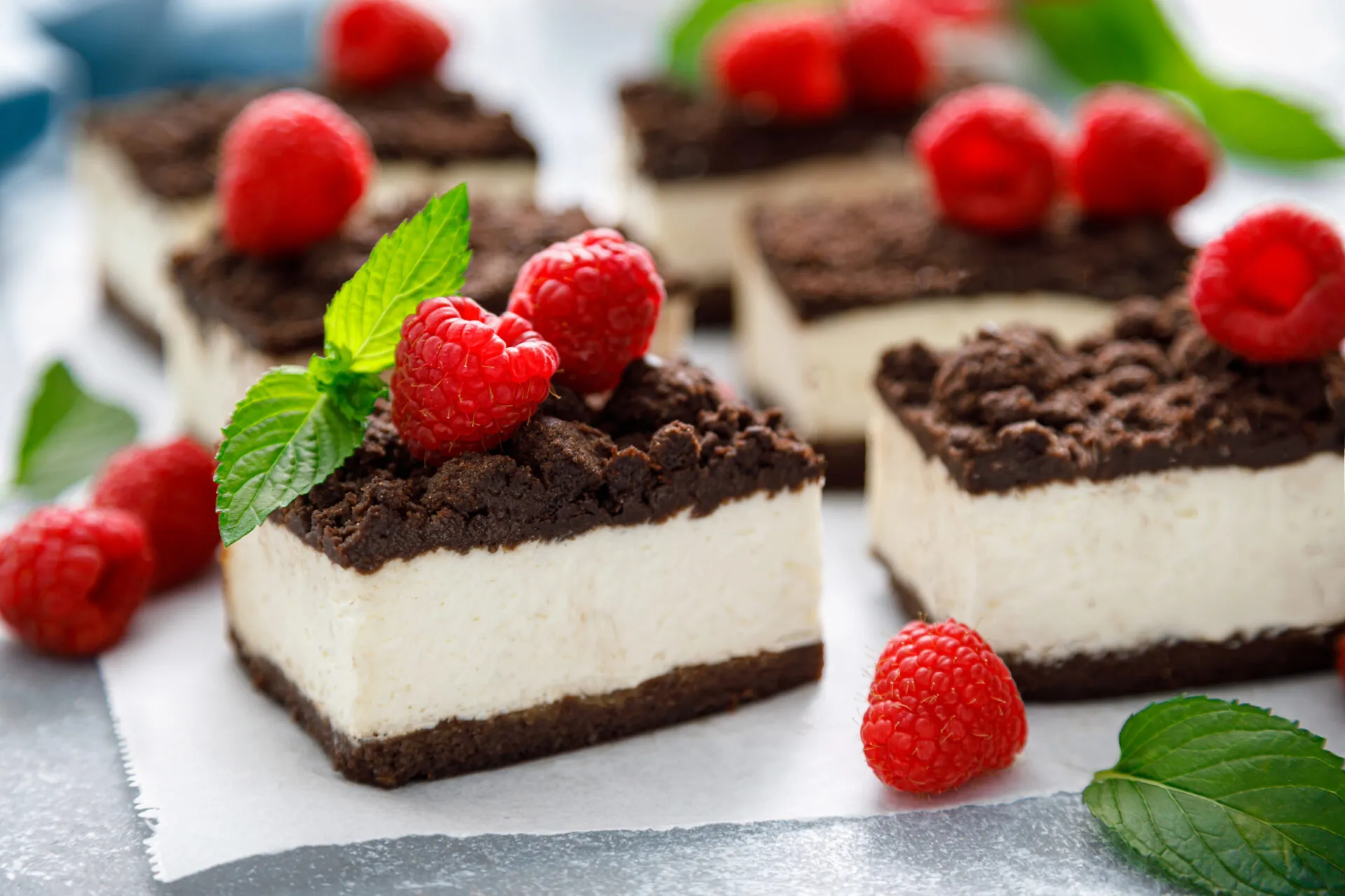 Quadrotti di cheesecake con base al cacao, crema bianca e lamponi
