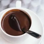 Cioccolata calda densa in tazza bianca con il cucchiaino