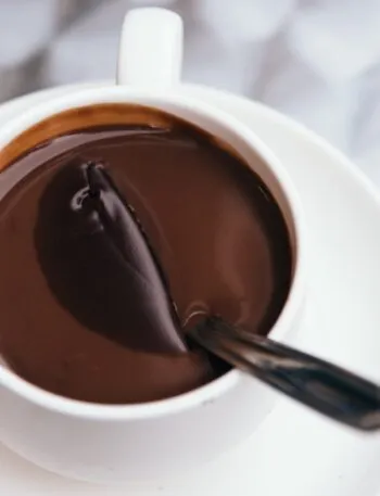 Cioccolata calda densa in tazza bianca con il cucchiaino