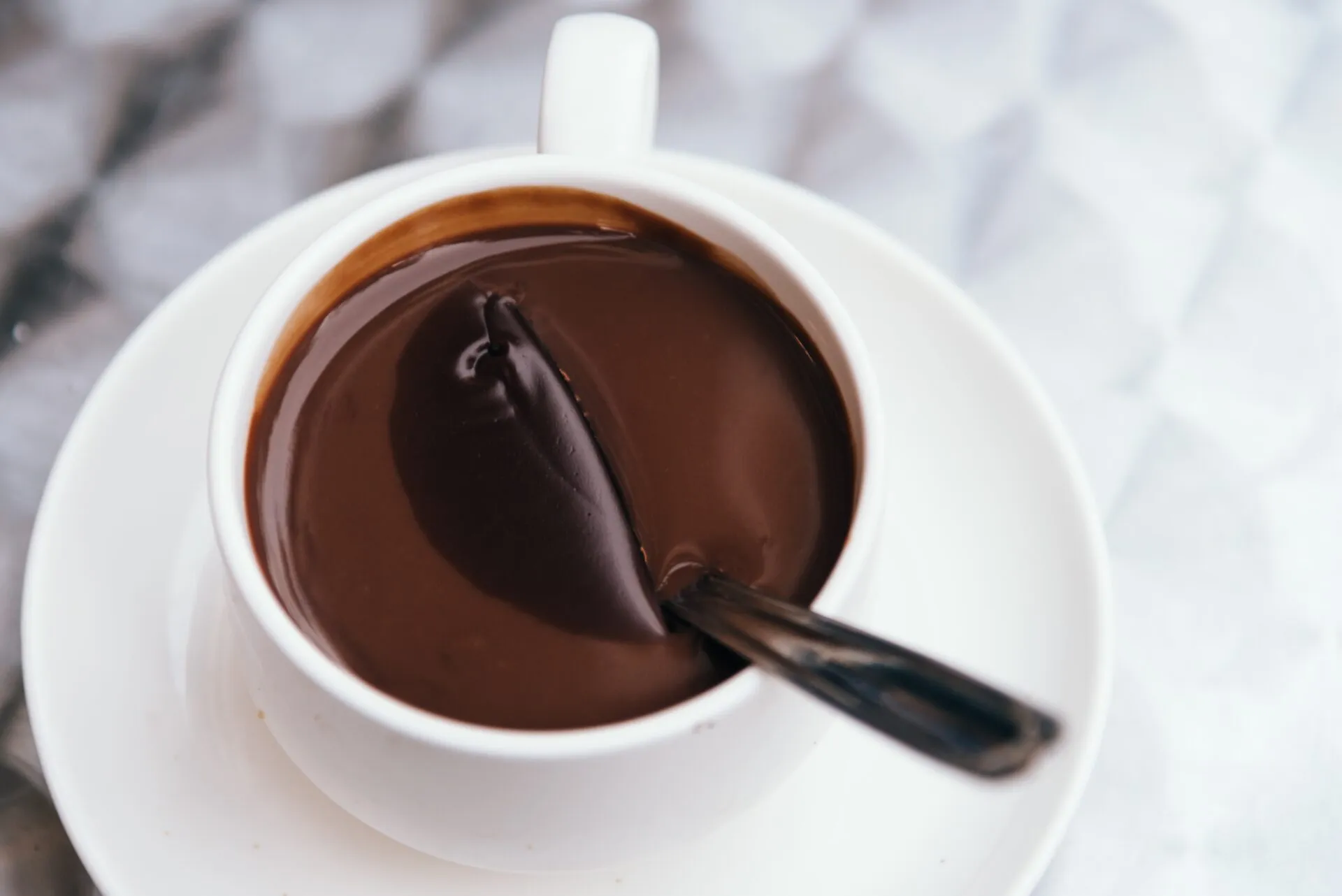 Cioccolata calda densa in tazza bianca con il cucchiaino