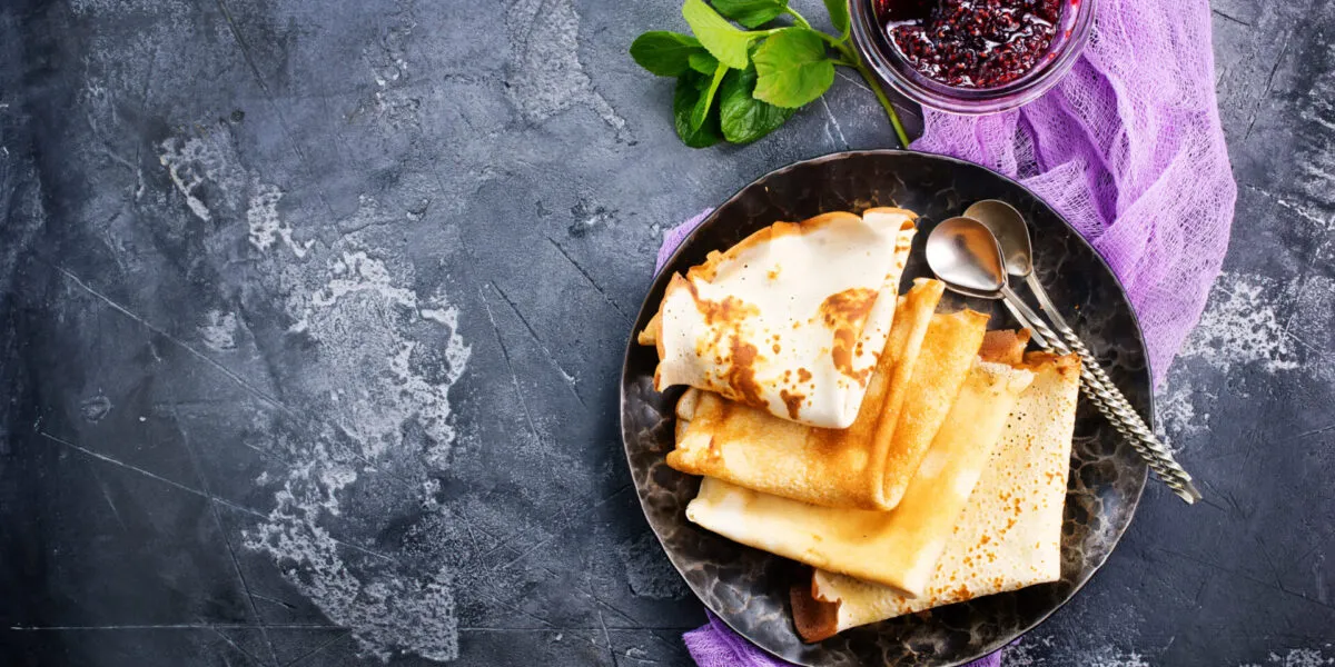 Crêpes piegate su un piatto scuro con confettura di frutti rossi