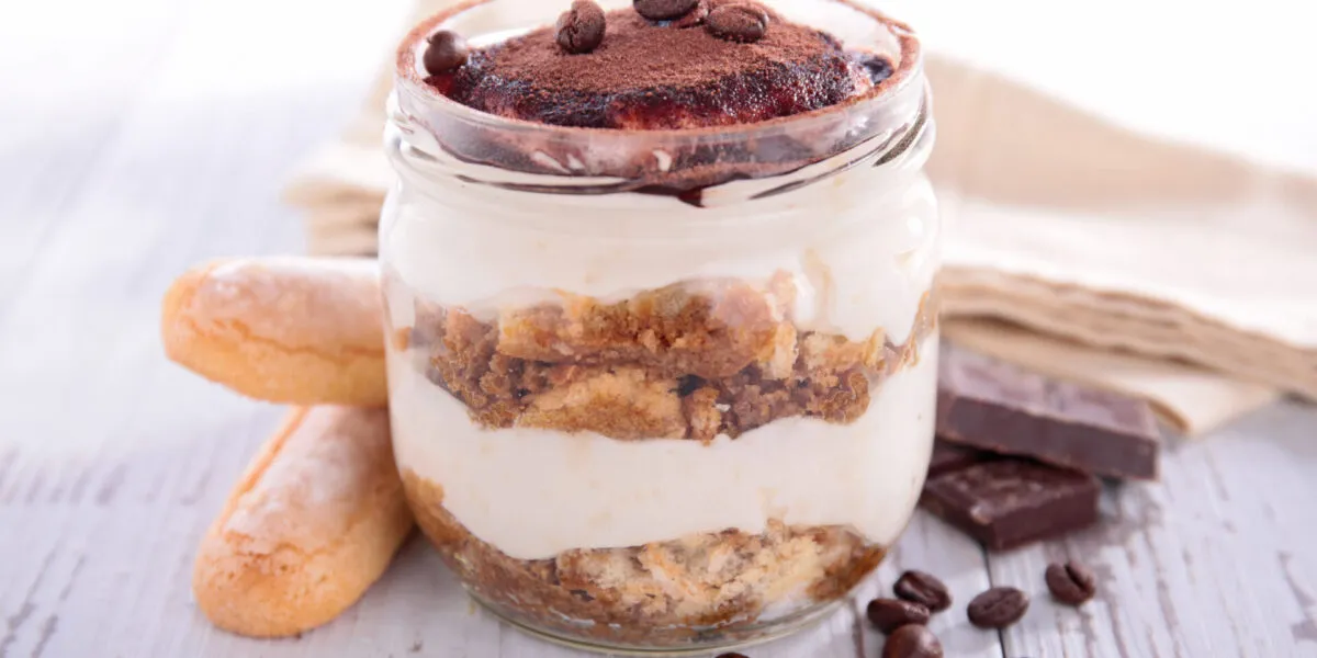 Tiramisù in vasetto di vetro con strati di crema, savoiardi e cacao