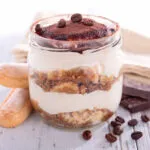 Tiramisù in vasetto di vetro con strati di crema, savoiardi e cacao