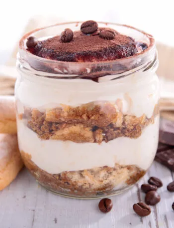 Tiramisù in vasetto di vetro con strati di crema, savoiardi e cacao